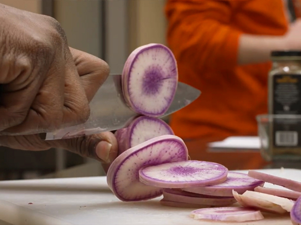 A closeup of slicing vegetables.