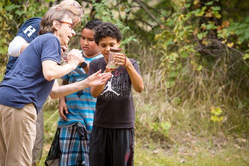 Youth and educators viewing jars of insects at NatureFest