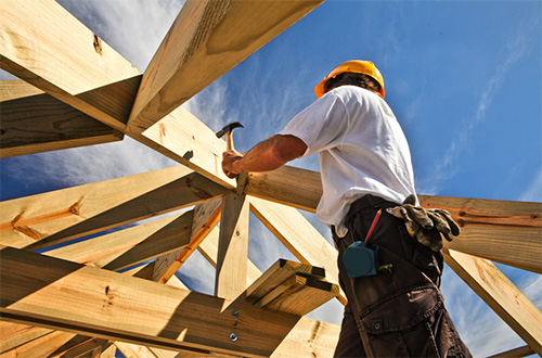 Construction worker in the sun working on house framing