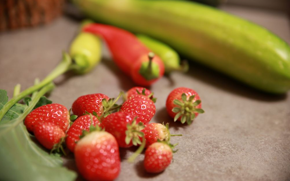 Strawberries and peppers on a counter.