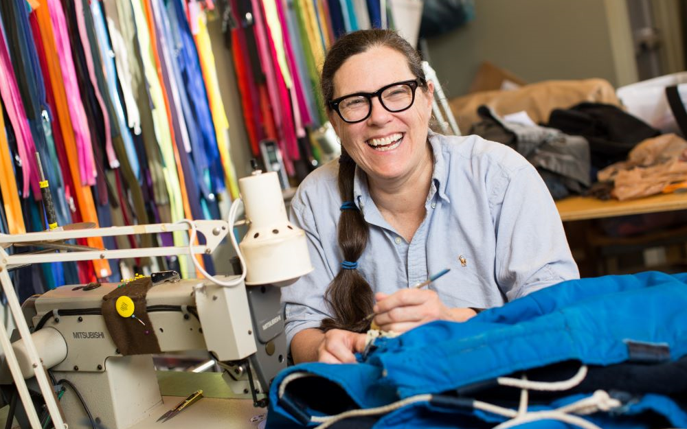 Smiling woman using sewing machine.