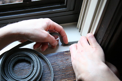 Person installing window weatherization strip.