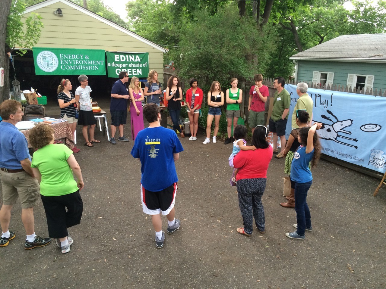 Neighbors in driveways standing in circle talking about climate solutions