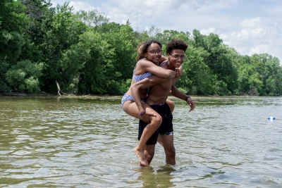 Man giving woman piggyback ride in shallow water at beach