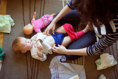 Overhead shot of baby laying on the floor while mom fastens a reusable diaper