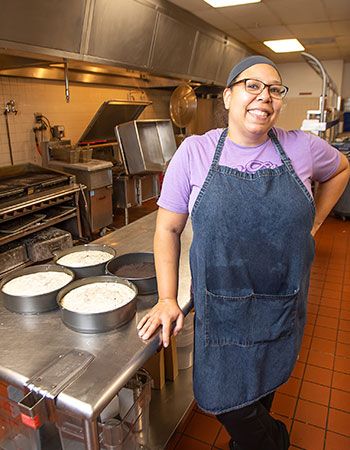 women standing by her cheesecake at her business