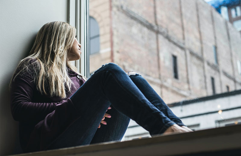 young girl sitting looking out the window