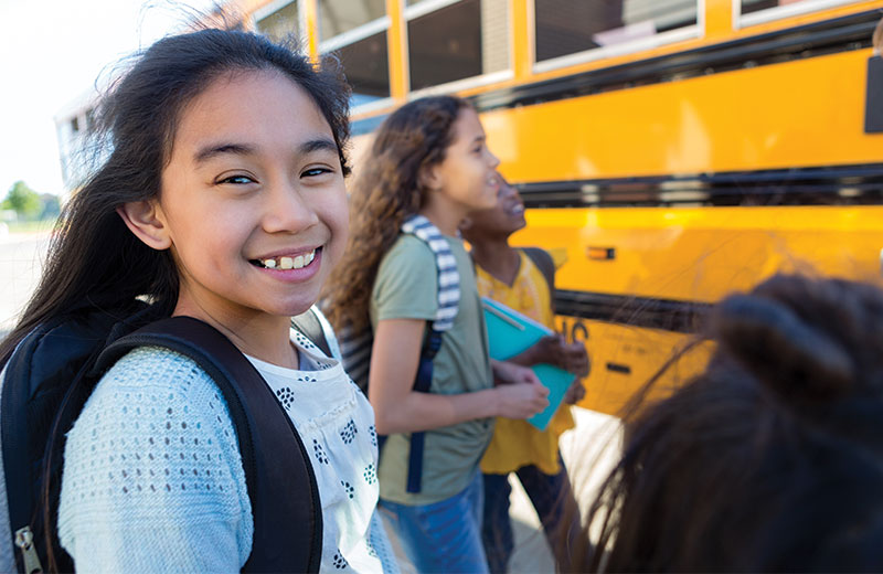 girl standing by school bus